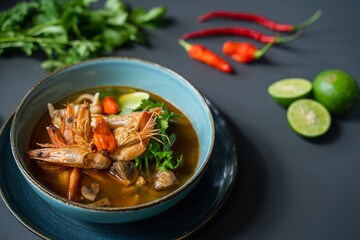 A bowl of food with shrimps and vegetables on a table.