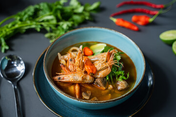 A bowl of food with shrimps and vegetables on a table.