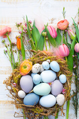 Beautiful easter card with Easter eggs in a nest and spring flowers on rustic wooden table - top view - easter decoration - greeting card