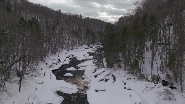 Aerial scenic drone down motion Canadian  wilderness mid winter near north Quebec Stoneham Ski Resort of frozen over Sautaurski River
