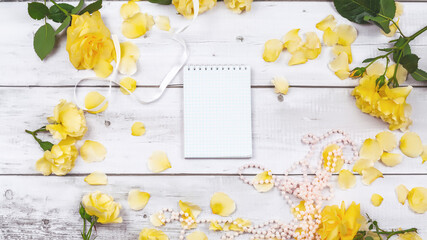 The composition of flowers. A yellow rose flowers on a white wooden background. The apartment was lying, top view, space for copying.