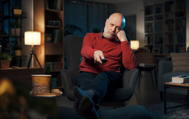 Bored senior man watching TV at night