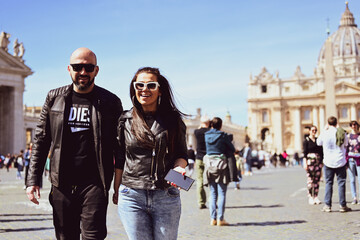Obraz na płótnie Canvas Happy smiling beautiful Tourists couple traveling at Rome, Italy, poses and making photos in front of Vatican City at, Rome, Italy.Concept of Italian gastronomy and travel. Italian couple having