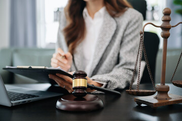 justice and law concept.law theme wooden desk, books, balance. Male judge in a courtroom the gavel,working with digital tablet computer