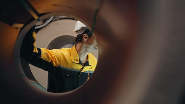 Hispanic Latino engineer man wearing hard hat and uniform holding tablet walking and checking aluminum rolls at the factory 
