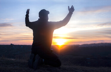 Prayer. A man on his knees. Pray at sunset. Kneeling