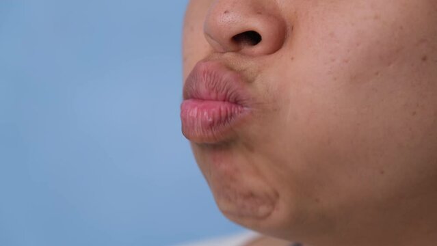 Young woman chewing gum and blowing bubble gum on blue background.