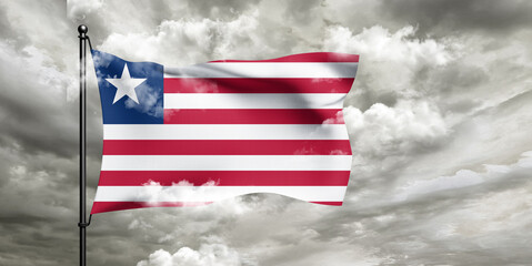 Liberia national flag cloth fabric waving on beautiful sky grey Background.