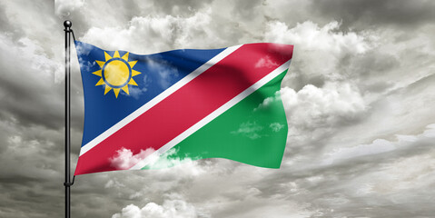 Namibia national flag cloth fabric waving on beautiful sky grey Background.