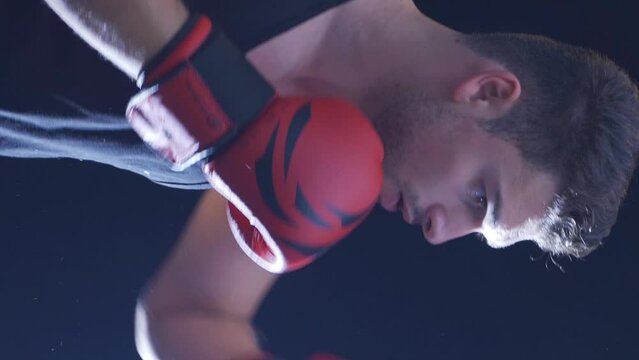 Vertical Video of Strong athlete punches punching bag in dusty gym. Cinematic boxing scene.
Young Boxer Beating the punching bag, training day at the boxing gym, strong body.
