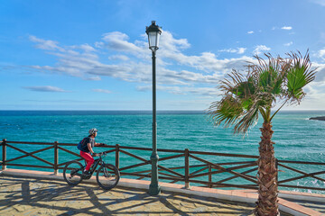 nice senior woman cycling with her electric mountain bike at the Costa Blanca coastline near Nerja, Andalusia, Spain