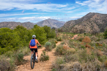 Fototapeta premium nice senior woman cycling with her electric mountain bike in the Sierra de Tejada near Nerja, Andalusia, Spain