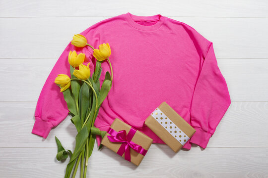 Closeup pink blank template sweatshirt hoodie copy space. Mothers women day yellow tulips, gifts. Happy birthday top view mockup pullover. White wooden background. Casual outfit. Flat lay templates