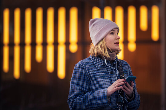 Young woman walking outdoors and using phone