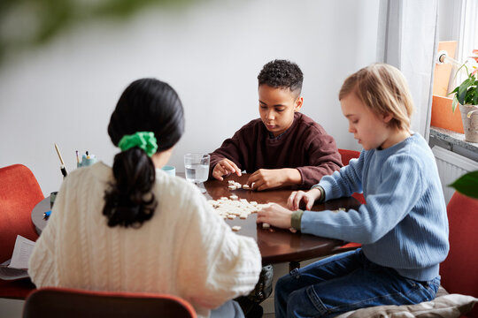 Girl and boys playing scrabble at dining table