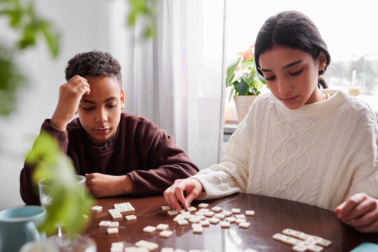 Girl and boy playing scrabble at dining table