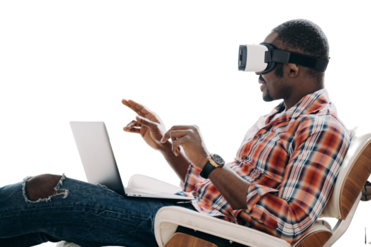 African american man wearing virtual reality glasses works in cyberspace at laptop, sitting in chair