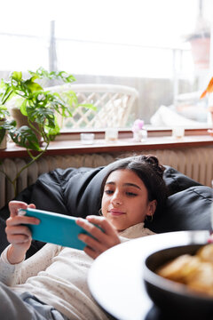 Girl lying on bean bag and playing video games
