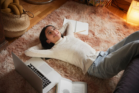 Girl with laptop lying on floor in her bedroom