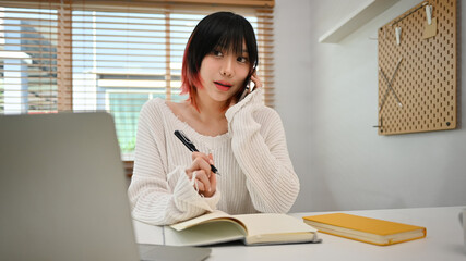 Young start up small business owner taking order from customer, talking on mobile phone at workplace