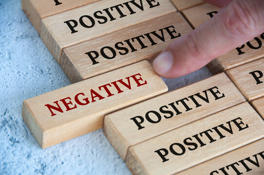 Finger pushing negative text on wooden block from the rest of the wooden blocks with positive text. Positive mindset concept.