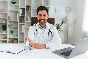 Obraz premium Sitting by a table. Doctor in formal clothes is working in the cabinet