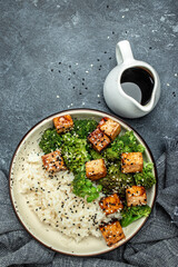 Vegan tofu poke bowl with rice and broccoli on a light background. Clean eating, dieting, vegan food concept. top view