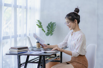 Pretty Asian woman using laptop while sitting at work concentrate on office work as an accountant Startup Business Executive Young female business leaders startup business ideas