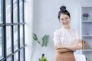 Smiling young beautiful Asian young woman, beautiful, confident and attractive in green sweater and eyeglasses in classroom or office. she was smiling happily