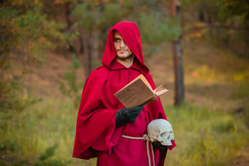 A sorcerer in red clothes with a skull and a book in his hands reads a spell. Medieval monk reads a prayer.