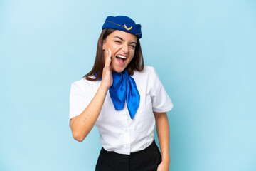 Airplane stewardess caucasian woman isolated on blue background shouting with mouth wide open