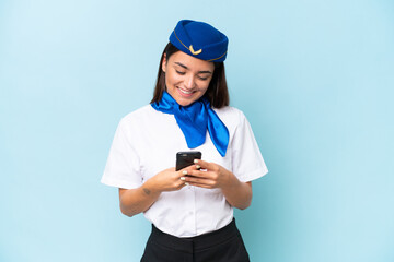 Airplane stewardess caucasian woman isolated on blue background sending a message with the mobile