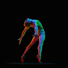 Obraz premium Contemporary art ballet. Young flexible athletic man, dancer jumping up in air over dark studio background with neon light. Modern dance style