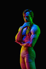 Portrait of serious muscle man, actor, dancer posing over dark studio background with neon light. Weightless, flexible. Modern ballet dance