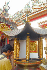 Visitor Paying Respect after Placing Incense Sticks in the Burner at Chinese Buddhist Temple