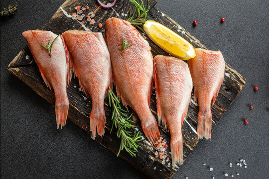 Fish red snapper on a wooden cutting board on a dark background. Healthy food concept. place for text, top view