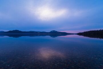 夜明けの空を湖面に反射する湖。北海道の屈斜路湖。