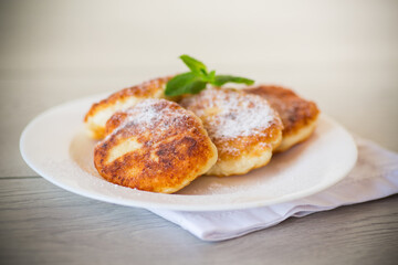 Sweet cooked cheesecakes in powdered sugar in a plate