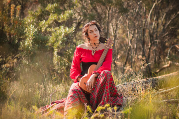 A young woman with dark country style hair in a red peasant jacket and plaid skirt holding a mini...