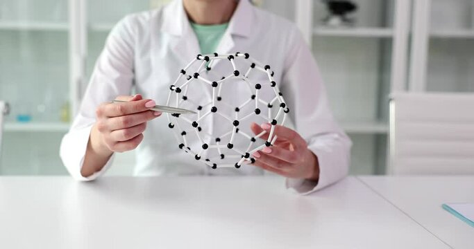 A woman holds a model of connection of molecules, a close-up. Creating a new formula, pharmacology