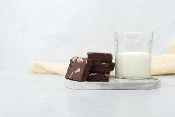 Brownies and milk glass on stone texture background. Chocolate brownie with sliced almond nuts toppings. Chocolate Brownie pieces. selective focus.