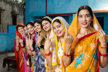 Election in india. Group of happy traditional indian women standing in queue showing their finger...