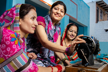 Portrait happy traditional indian woman wearing sari teaching other females how tu use sewing machine. Skill india Concept.