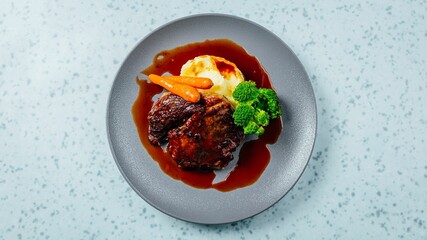 Closeup shot of a gourmet dish with steak, vegetables, and sauce on a table