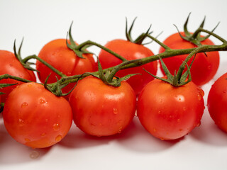 Bunch of fresh red tomatoes with green stems isolated on white background. Tomatoes close-up.