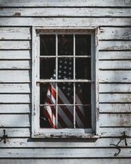 American Flag is displayed in the window of a rustic wooden building, fluttering in the breeze