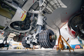 Commercial airplane under heavy maintenance. Close-up of landing gear of plane during repair..