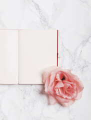 Open notebook decorated with roses isolated on white marble background. Flat lay. Top view. Copy space.