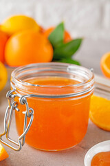 Orange marmalade or orange jam in glass jar with fresh fruits on a gray background. Copy space.