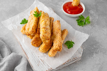 Baked crispy garlic parmesan zucchini sticks served with tomatoes sauce on a gray concrete background. Vegetarian healthy dish. Selective focus.